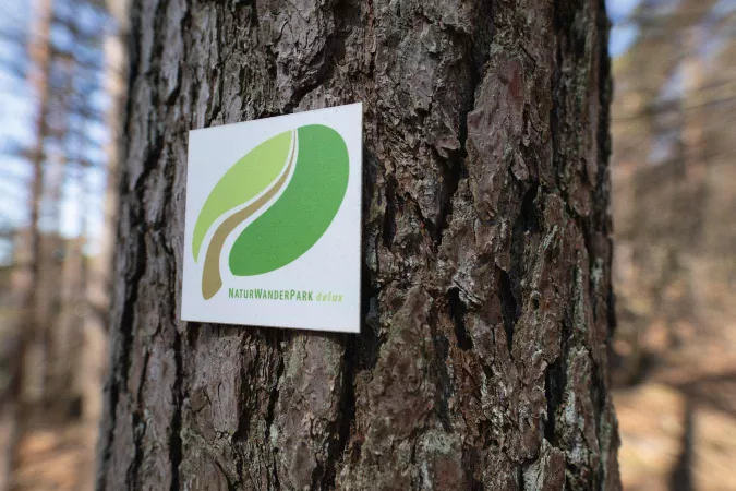 Schild "Naturpark Delux" am Baum
